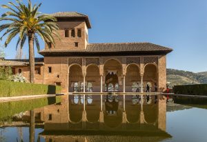 wide angle shot of a building in front of the water and next to the tree in spain