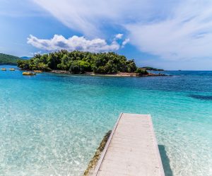 a view along a wooden jetty towards islands offshore from the beach at ksamil, albania in summertime