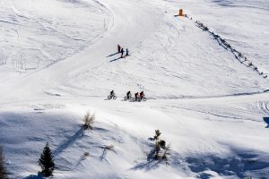 beautiful view of people cycling and skiing across snowy mountains in south tyrol, dolomites, italy